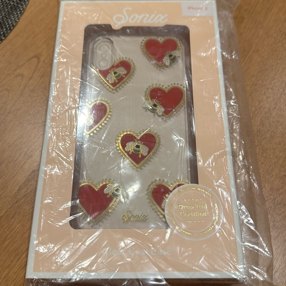 New in box/plastic - iPhone X case. Clear with red hearts and bumblebee detail.